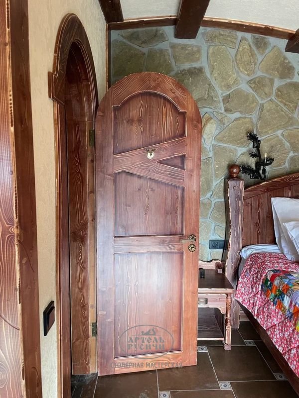 Мебель для гостиницы: на фото дверь и откосы из массива сервной сосны, деревянная прикроватная тумбочка и кровать под старину
