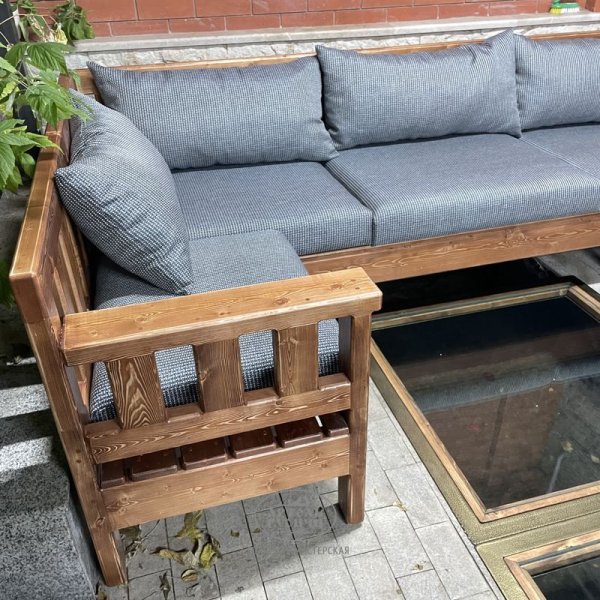 Садовый диван П-образной формы из массива дерева с мягкими подушками фото крупный план
